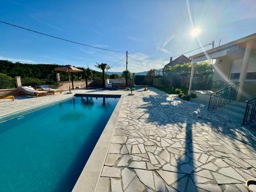 una piscina con una pasarela de piedra junto a una casa en Sunny village, pool house, en Podgorica