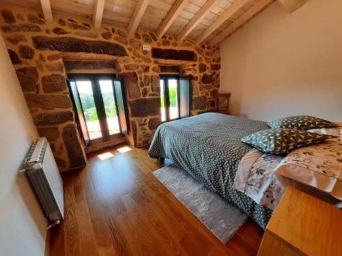 um quarto com uma cama e uma parede de pedra em CASA DO EIRÓ em Lobios