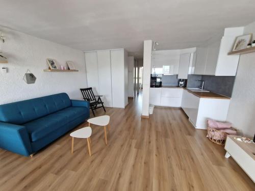 un salon avec un canapé bleu et une cuisine dans l'établissement Appartement Cap d'Agde avec vue mer, au Cap d'Agde