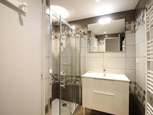 une salle de bain avec un lavabo et une douche en verre dans l'établissement Charmant T2 au Mont-Dore, parking privatif, proche thermes, classé 2 étoiles - 4 couchages - FR-1-415-124, à Le Mont-Dore