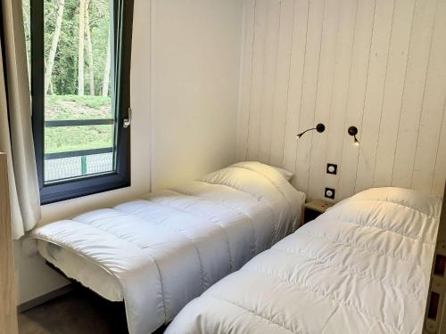 deux lits dans une chambre avec une fenêtre dans l'établissement Chalet à Jullouville - 6 couchages, piscine chauffée, proche plage et commerces - FR-1-361-521, à Jullouville