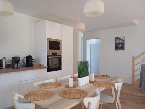 une salle à manger avec une table et des chaises dans une cuisine dans l'établissement Maison 8 pers, proche plage et commerces, jardin, barbecue, équipements bébé, linge inclus - FR-1-639-122, à Arzon