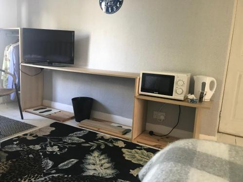 a living room with a tv and a microwave at School Lodge in Norwich