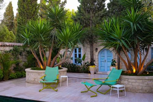 two green chairs sitting on a patio with palm trees at Alaçatı Taş Otel in Alacati
