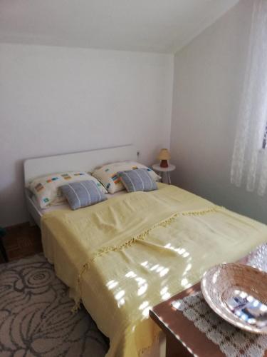 a bedroom with a bed with yellow sheets and pillows at Apartman Brazil in Bihać