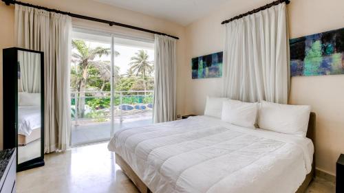 - une chambre avec un lit blanc et une grande fenêtre dans l'établissement Watermark Luxury Oceanfront Residences, à Cabarete