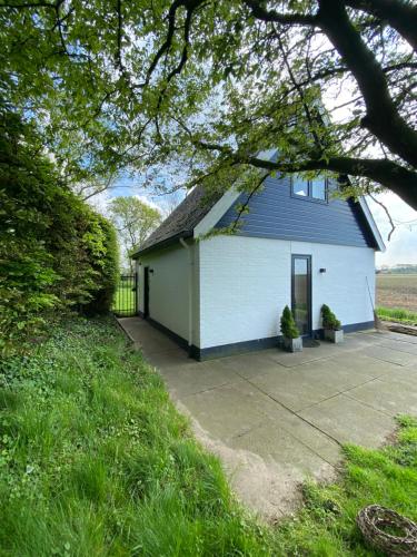 a white and blue house with a driveway at Guesthouse The White House - gehele huisje in Klaaswaal