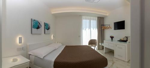 a white bedroom with a bed and a desk at Donna Adriana Rooms in Agropoli