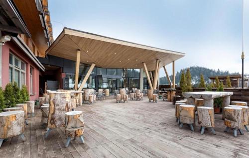 a patio with tables and chairs and a building at Apartmani VinVucko Jahorina u sklopu aparthotela Vucko privatni apartmani in Jahorina