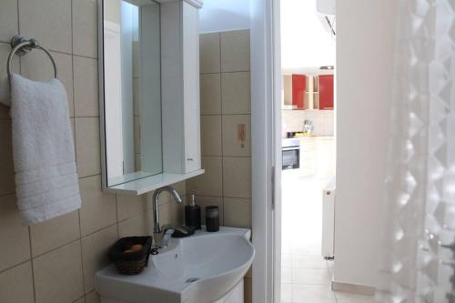 a white bathroom with a sink and a mirror at Apartment Lucia in Argostoli