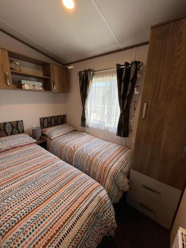 a bedroom with two beds and a window at Visma Caravan in Llanddwywe