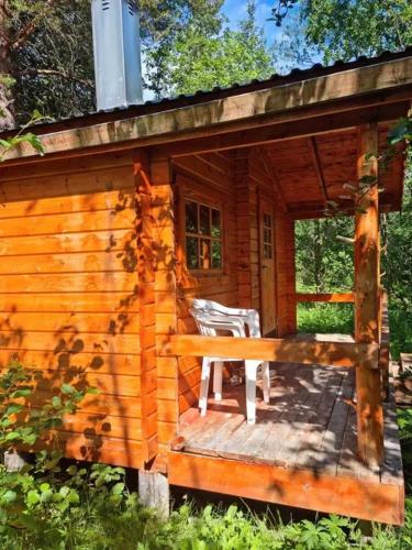 a log cabin with a bench on a deck at Tørfoss Gård, Hytte utleie, Campingvogn og bobil plasser in Potka