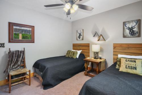 a bedroom with two beds and a fan and a chair at Large Cabin to Enjoy in Coosawattee River Resort in Ellijay