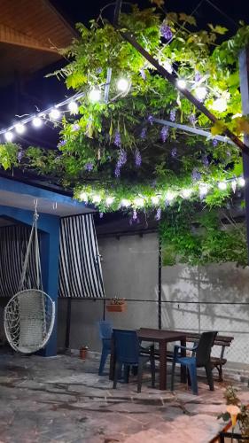 een patio met een tafel en stoelen en paarse bloemen bij Makos Guest House in Koetaisi