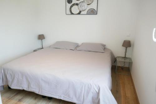 une chambre avec un grand lit blanc avec deux lampes dans l'établissement Les Pivoines Maison climatisée, proximité mer, plages et forêts, à Saint-Hilaire-de-Riez