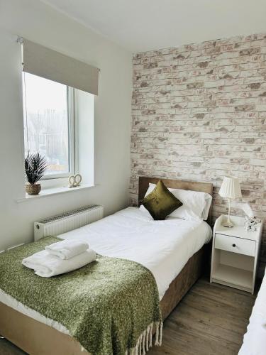 a bedroom with a bed and a brick wall at Modern, spacious house near town in Peterborough