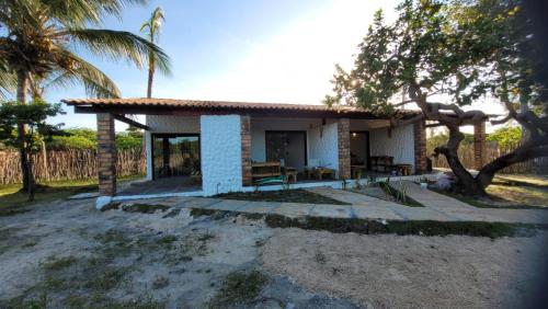 a small white house with a porch and palm trees at Vila Capininga Ecopousada in Santo Amaro