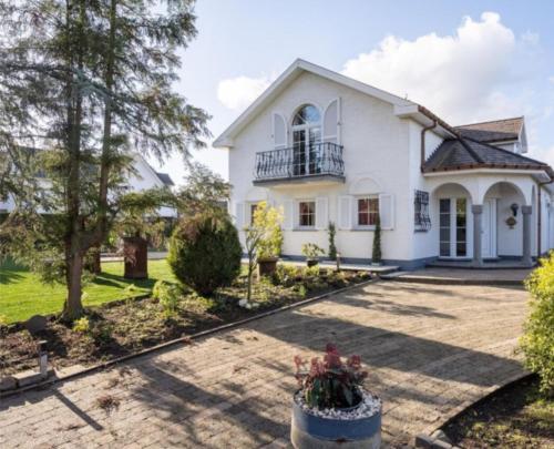 a large white house with a courtyard at Villa kleinwellness in Lanaken