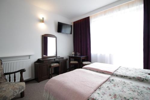 a bedroom with a bed and a mirror and a chair at Motel Na Zbójeckiej in Skawa