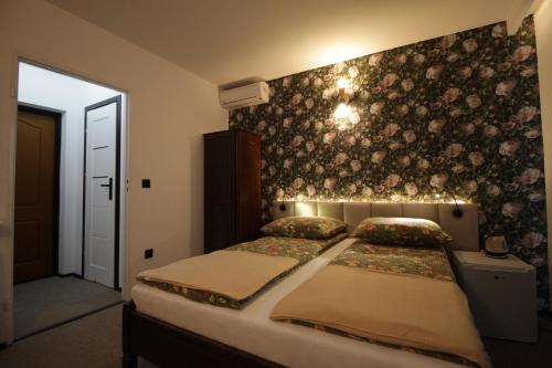 a bedroom with a bed and a wall with flowers at Motel Na Zbójeckiej in Skawa