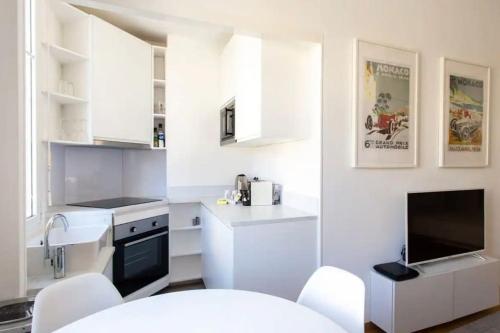 une cuisine blanche avec des armoires blanches et un évier dans l'établissement Charming Flat at Monaco's Edge, à Beausoleil