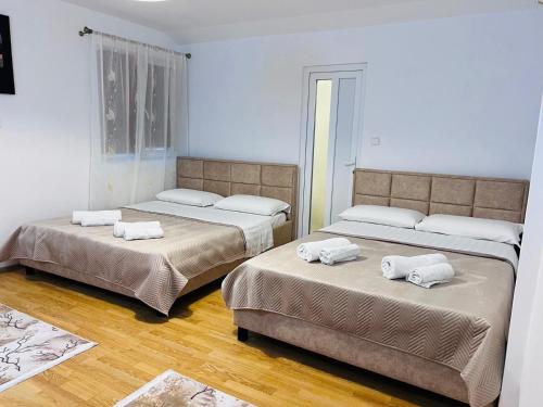 two beds in a room with white walls and wood floors at IMPERIUM DK VILLA in Remuş