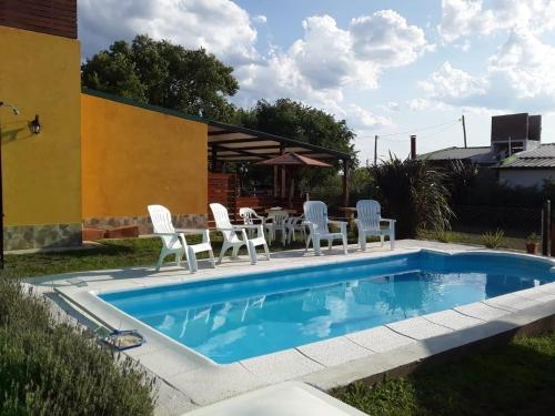 einen Pool mit weißen Stühlen und einem Tisch in der Unterkunft Complejo Rancho Aparte in Villa Rumipal