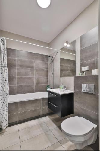 a bathroom with a toilet and a sink and a tub at Airport Apartament Bokserska in Warsaw