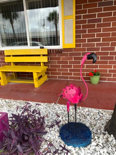 a flamingo statue in front of a house with a bench at Seahorse Inn in New Smyrna Beach