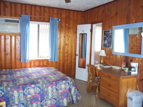 a bedroom with a bed and a dresser and a desk at Seahorse Inn in New Smyrna Beach