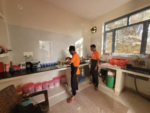 two men standing in a kitchen preparing food at 11 Gaon Homestay Lansdowne in Lansdowne