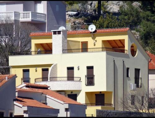 a yellow house with a balcony on top of it at House DMS in Tisno