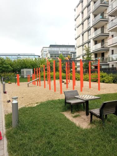 a park with benches and orange poles in the sand at Airport Apartament Bokserska in Warsaw