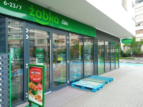 a store front with a blue bench outside of it at Airport Apartament Bokserska in Warsaw