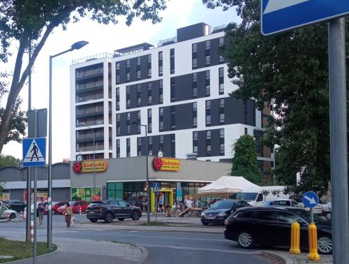 a parking lot with cars parked in front of a building at Airport Apartament Bokserska in Warsaw