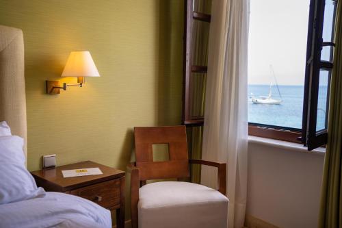 a room with a bed and a chair and a window at La Boheme Hotel in Gythio