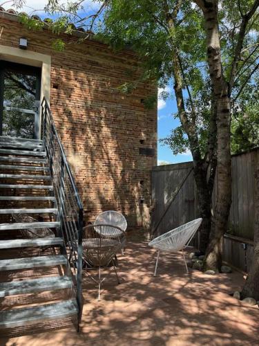 two chairs and a staircase next to a brick building at Cosy Appartement Escapade Label Braise, terrasse et parking in Ségoufielle