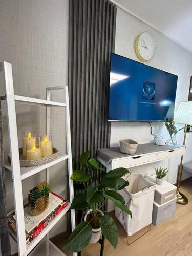 a living room with a tv on a white shelf at Cozy Condo in Clark Pampanga with Free Parking & Pool Access in Mabalacat