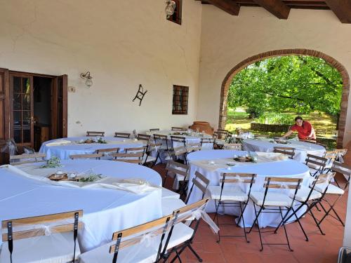 une chambre avec des tables et des chaises blanches avec une personne en arrière-plan dans l'établissement Podere Fichereto Tuscany apartment in Florence countryside, à Scandicci