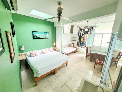 a bedroom with a white bed and a green wall at ITH Sayulita Amazing Surf Hostel in Sayulita