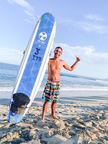 a man standing on the beach with a surfboard at ITH Sayulita Amazing Surf Hostel in Sayulita