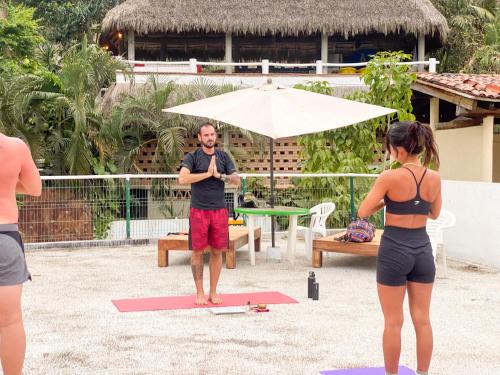 a man standing on a yoga mat on the beach with two women at ITH Sayulita Amazing Surf Hostel in Sayulita