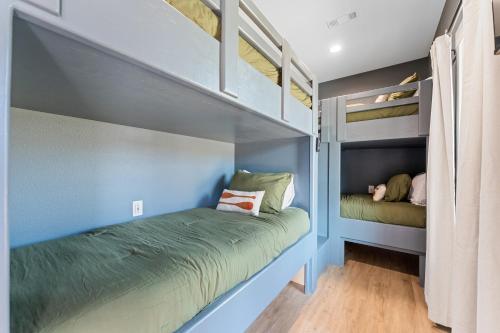 two bunk beds in a room with blue walls at New Ozark Oasis Luxe Cabin Retreat with Hot Tub in Hollister