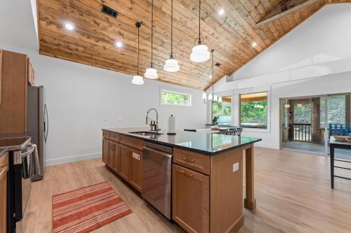 an open kitchen with wooden ceilings and a large island at New Ozark Oasis Luxe Cabin Retreat with Hot Tub in Hollister