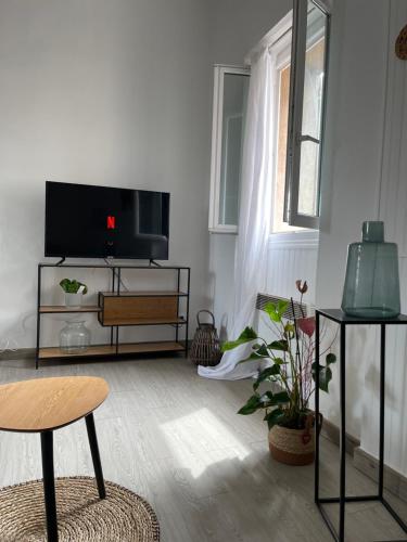 un salon avec une télévision et une table dans l'établissement Appartement proche plage et centre ville, à Saint-Laurent-du-Var