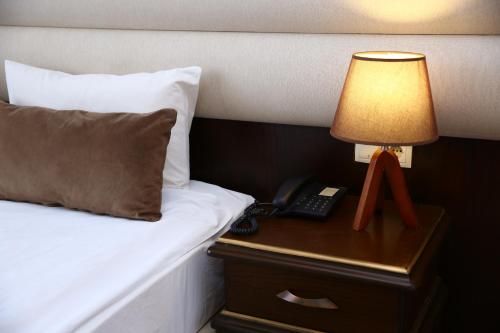 ein Bett mit einer Lampe und einem Telefon auf einem Nachttisch in der Unterkunft Smith Hotel Baku in Baku