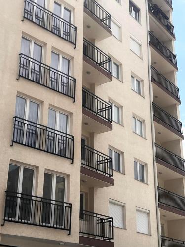 a tall building with balconies on the side of it at Fushe Kosove Cozy Apartment in Kosovo Polje