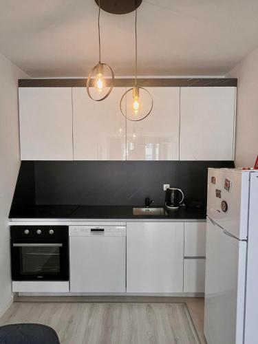 a kitchen with white cabinets and a black counter top at Fushe Kosove Cozy Apartment in Kosovo Polje