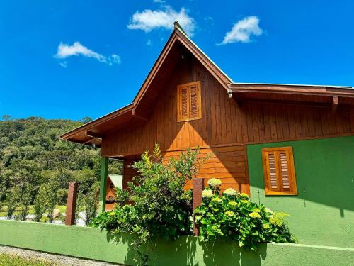 a green and wooden house with some plants in front at Vila Vert - Rancho Queimado - SC in Rancho Queimado