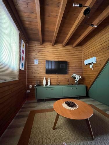 a living room with a table and a tv at Vila Vert - Rancho Queimado - SC in Rancho Queimado